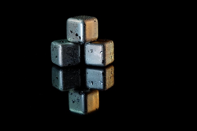 Stainless steel cubes simulating ice for cooling drinks on a black surface with a reflection