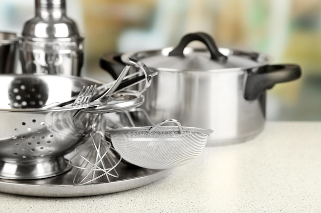 Stainless steel kitchenware on table on light background