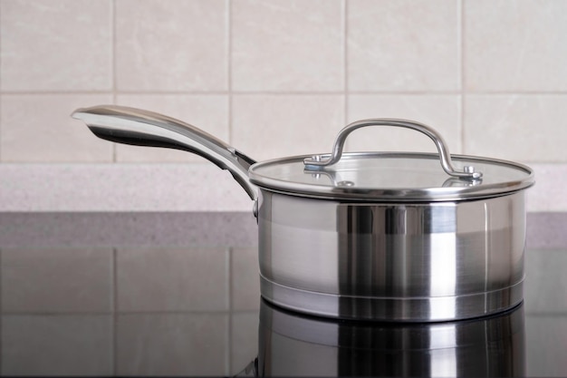 Stainless steel ladle sits on modern stove with glassceramic hob