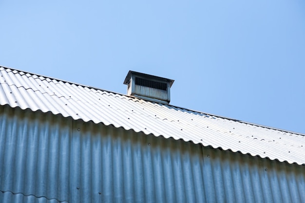 Stainless steel metal chimney pipe on the roof of the house against the sky.