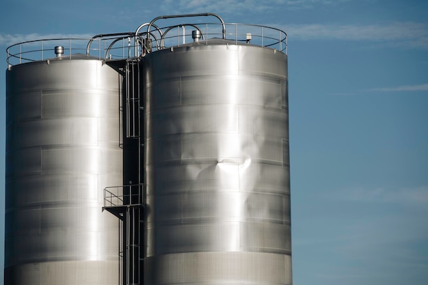 Stainless steel silos in the chemical industry bulk plastics silo against a sun orange