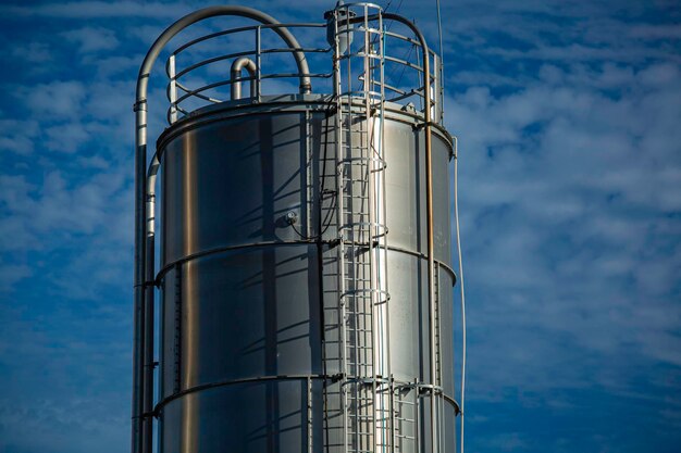 Photo stainless steel silos in the chemical industry bulk plastics silo against a sun orange