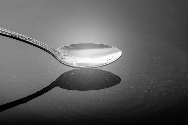 Photo stainless steel spoon above the water reflection.
