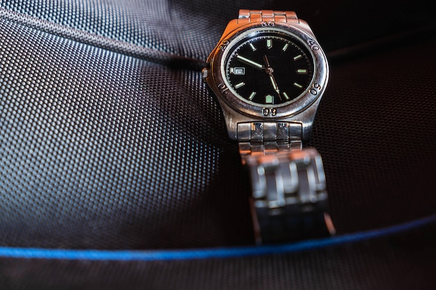 A stainless steel watch on a black background