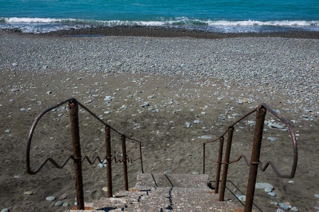 Staircase to beach Blue water and stones on beach