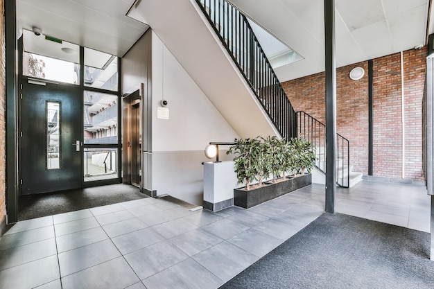 Staircase and elevator located near door and brick wall in hall of contemporary apartment building