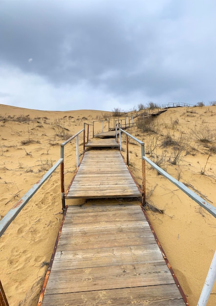 The staircase rises to a sandy dune Climbing to the top in the desert