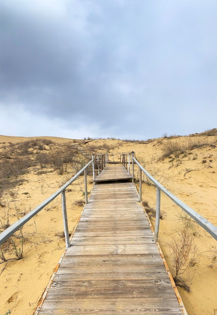 The staircase rises to a sandy dune Climbing to the top in the desert