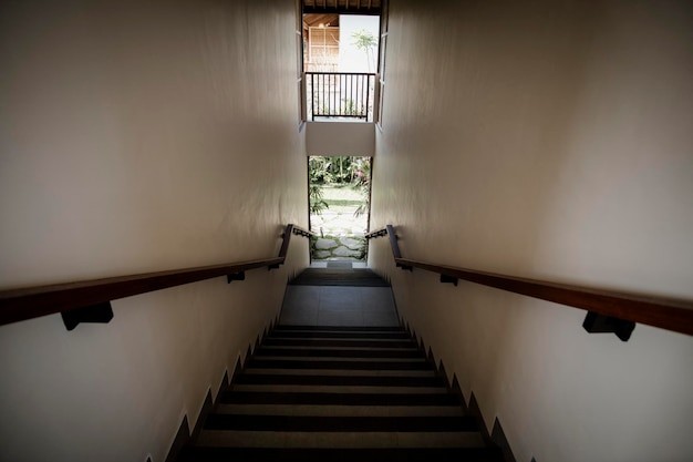 A staircase with a wooden handrail and a sign that says " the word " on it.