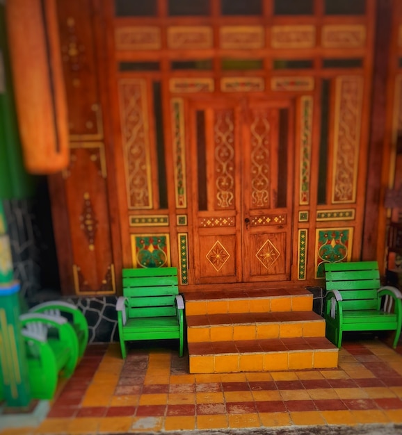 Photo the stairs to the beautiful house are made of dark yellow tiles with green chairs on each side