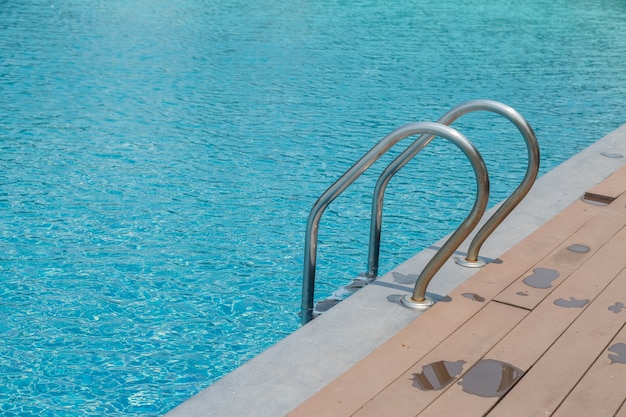 Stairs Ladder and handle down the swimming pool with blue water background