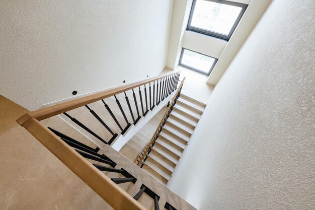 Stairs made of tiles in a new house metal black railing with\
wooden handrails