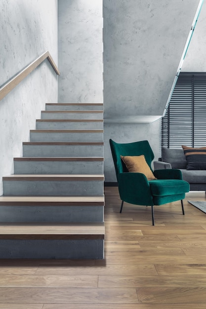 Stairs in modern living room interior Green velvet armchair and minimalist personal accessories