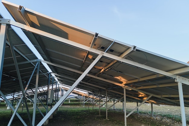 Stalen frame op de grond van een grote duurzame elektrische centrale met rijen fotovoltaïsche zonnepanelen voor het produceren van schone ecologische elektrische energie