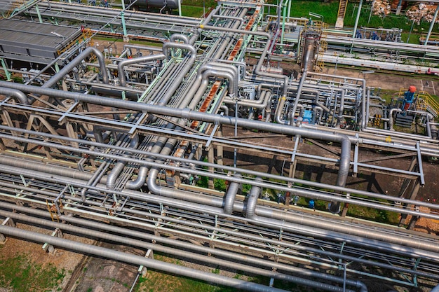 Stalen lange pijpen stromend symbool en pijpelleboog in de oliefabriek van het station tijdens de raffinaderij Petrochemie-industrie op de gassite