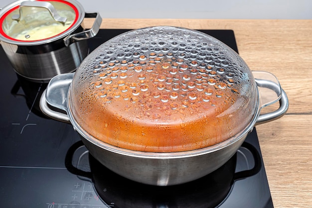 Foto stalen potten met een kookplaat op een inductieplater ingebouwd in de keukentafel op de kasten