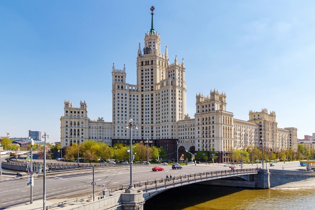 Stalin skyscraper on Kotelnicheskaya Embankment in Moscow on a background of Malyi Ustyinskiy Bridge in sunny morning