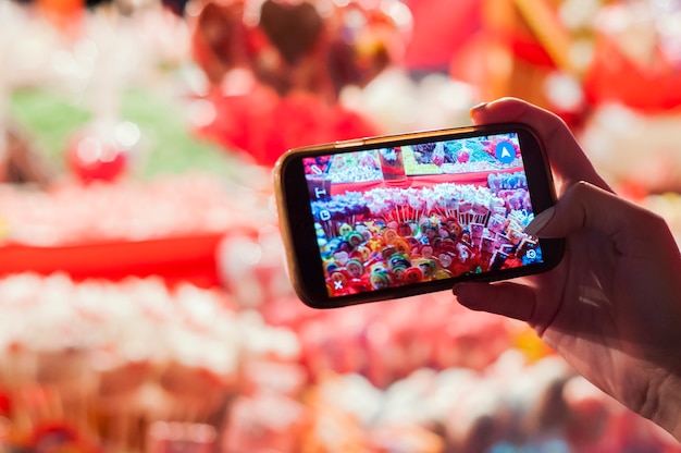 Stalletje met traditionele kleurrijke en feestelijke snoepjes op kerstmarkt, Veel kleurrijke snoepjes en lollipops op eerlijk. Meisje met smartphone fotograferen snoepjes, snoepjes en lollyjes