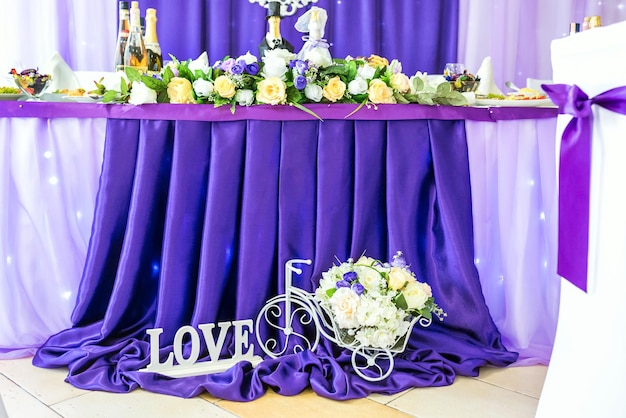 Подставка для цветов в виде велосипеда и надпись love возле праздничного стола