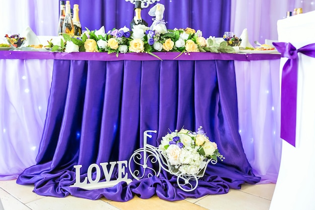 Stand for flowers in the form of a bicycle and an inscription love near the festive table