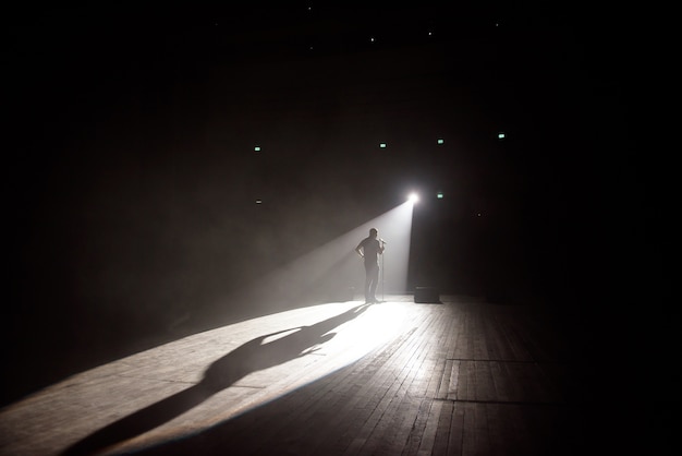 Stand up comedian on stage in the beam of light.