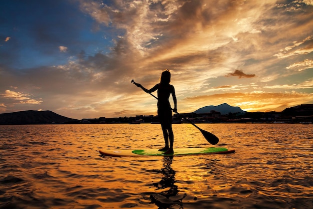 Photo stand up paddle boarding on a quiet sea with warm summer sunset colors