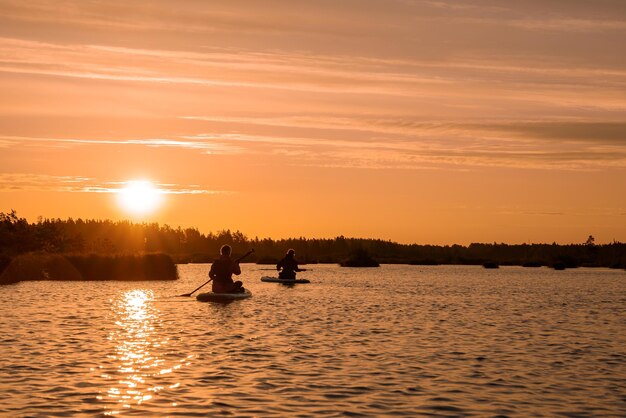 Stand up paddle boarding or standup paddleboarding on quiet lake at sunrise