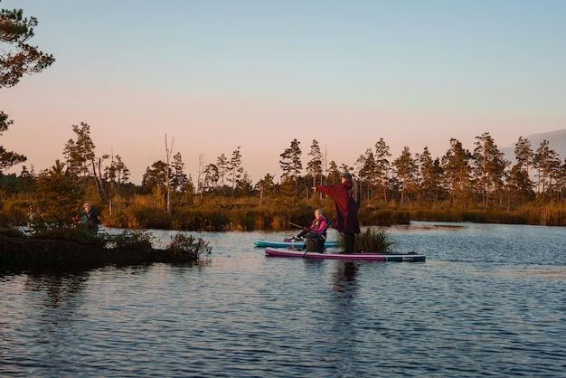 Foto stand-up paddleboarden of stand-up paddleboarden op een rustig meer bij zonsopgang