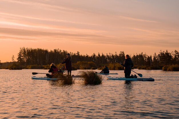 Foto stand-up paddleboarden of stand-up paddleboarden op een rustig meer bij zonsopgang