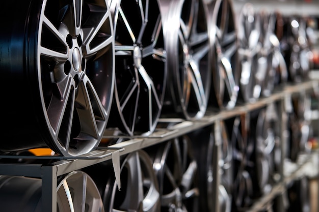 Stand with alloy wheels in modern tire store, close up photo of auto wheels in auto service shop