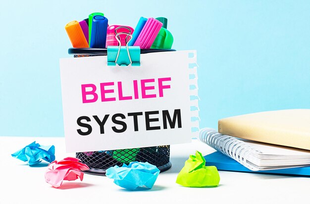 カラフルなフェルトチップペンのメモ帳と「BELIEFSYSTEM」というテキストが書かれた1枚の紙で立ちます