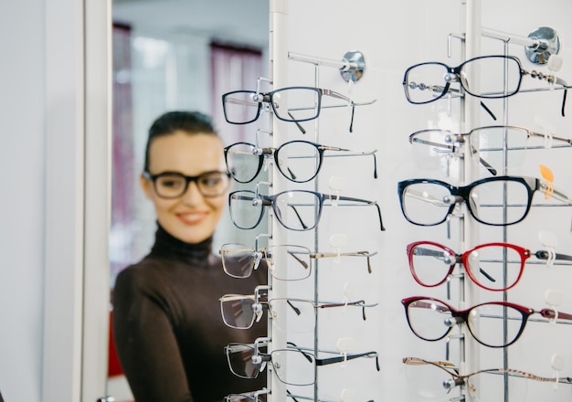 Stand with glasses in the store of optics Beautiful girl in glasses on a background Selective focus