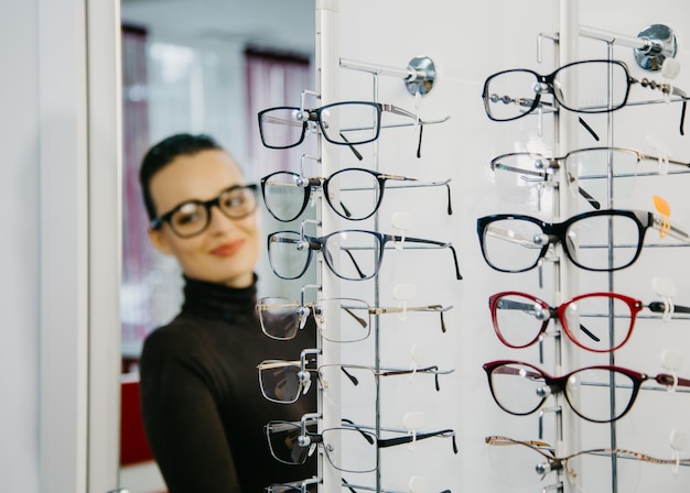 Stand with glasses in the store of optics Beautiful girl in glasses on a background Selective focus