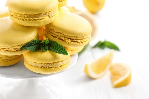 Stand with tasty lemon macarons on light table closeup