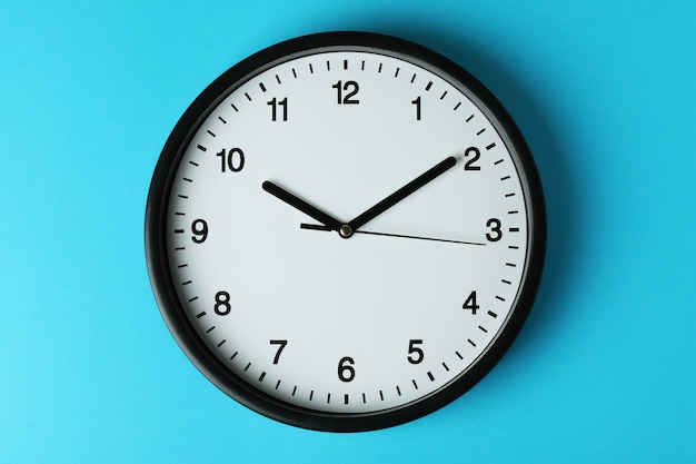 Standard black office clock on blue