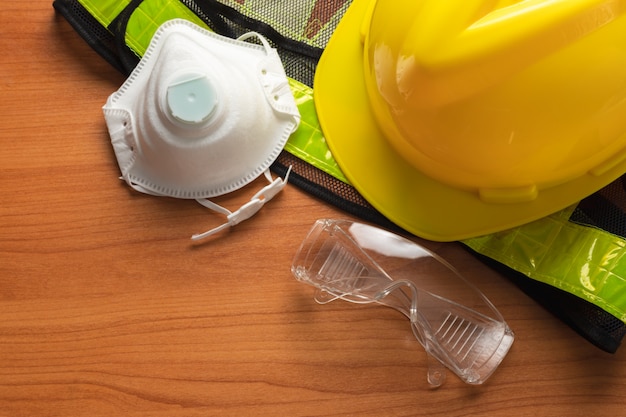 Standard construction safety glasses mask helmet Reflective shirt on wooden plank.