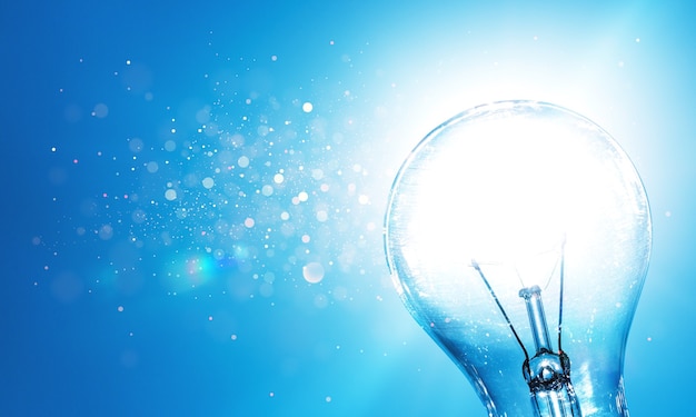 Standard incandescent light bulb on blue background