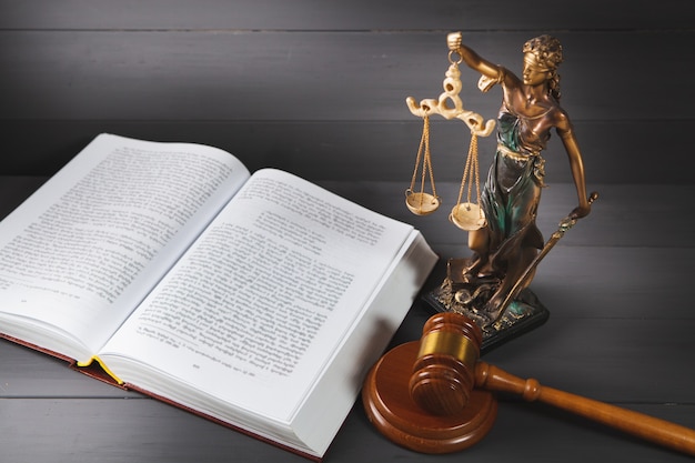 Standbeeld van Justitie, boek en hamer op houten tafel