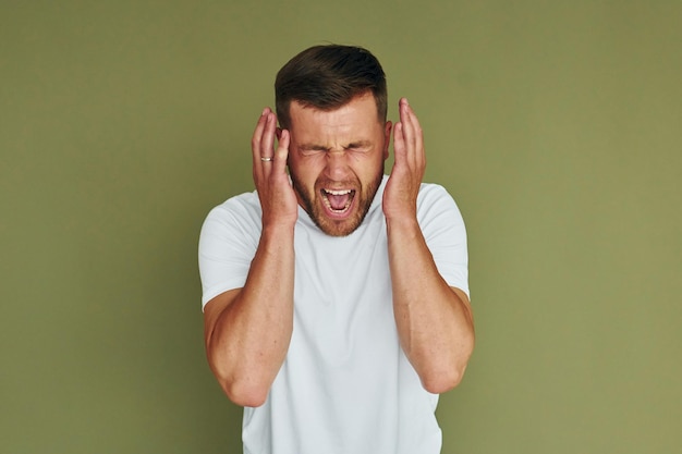 Standing against green background Young man in casual clothes indoors in the studio