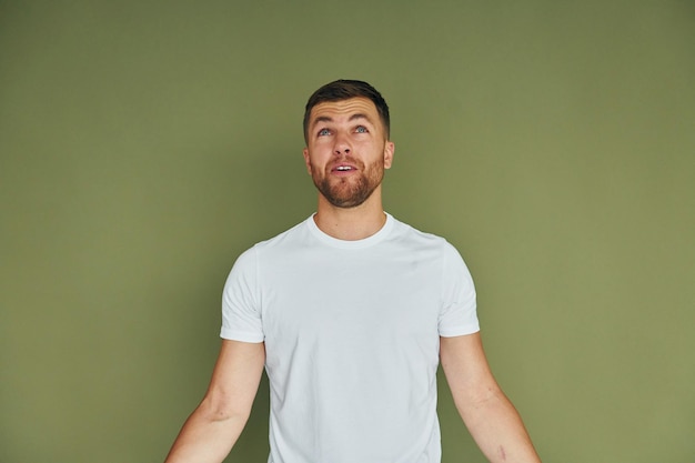 Standing against green background Young man in casual clothes indoors in the studio