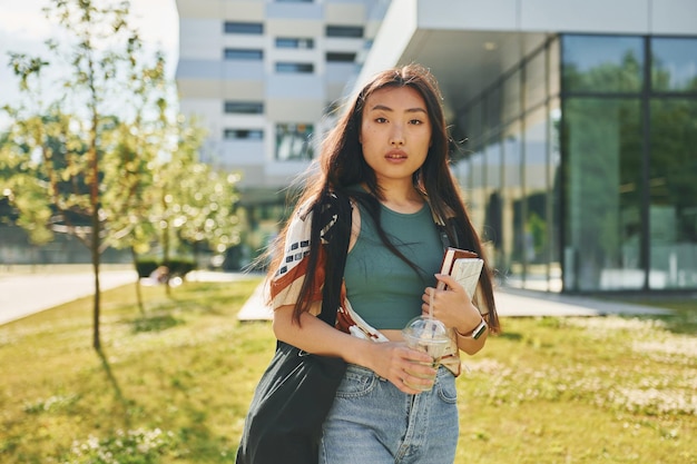 Photo standing against modern building young asian woman is outdoors at daytime