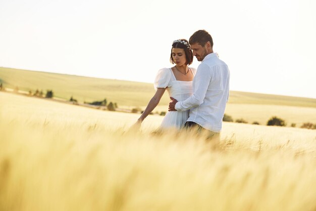 Photo standing and enjoying the nature couple just married together on the majestic agricultural field at sunny day