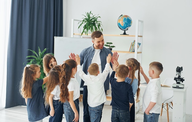 Standing and giving high fives group of children students in class at school with teacher