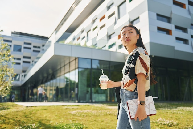 Standing on the grass Young asian woman is outdoors at daytime