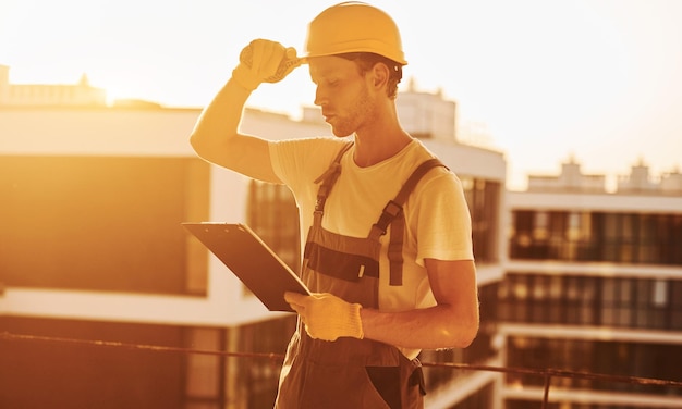 Standing high up Young man working in uniform at construction at daytime