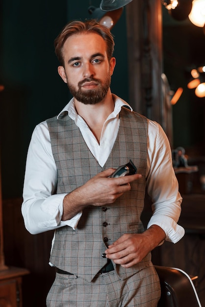 Standing holding equipment Handsome barber is in the salon