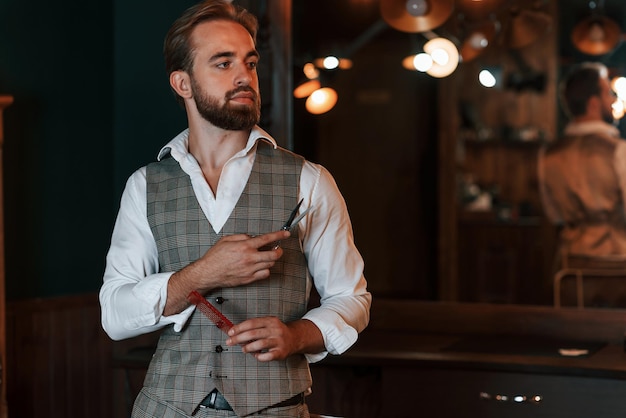 standing holding equipment handsome barber is in the salon
