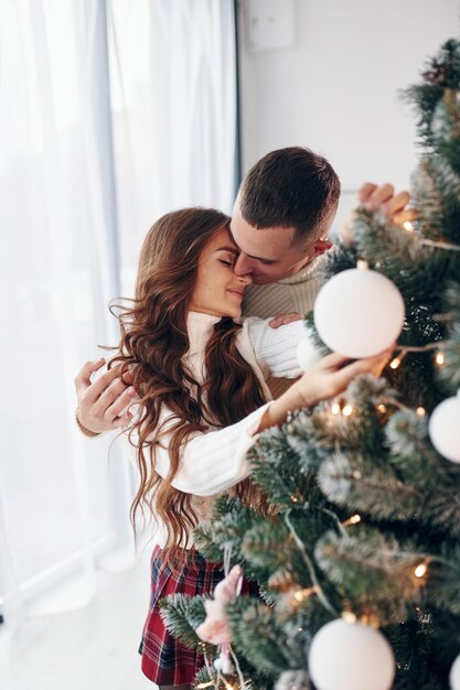 standing near fir young romantic couple celebrates new year together indoors