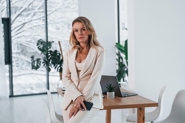 Standing near window Business woman in formal clothes is indoors posing for the camera