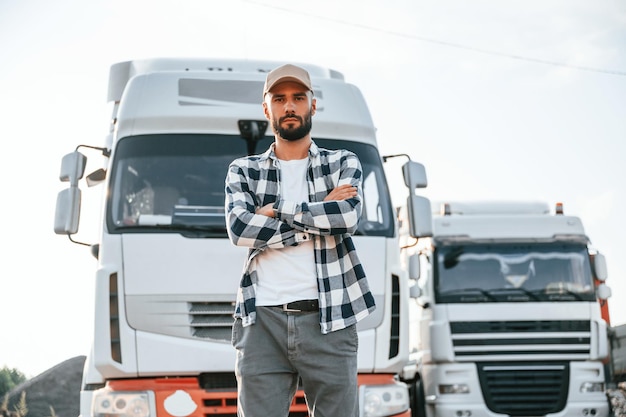 Photo standing outdoors young truck driver is with his vehicle at daytime